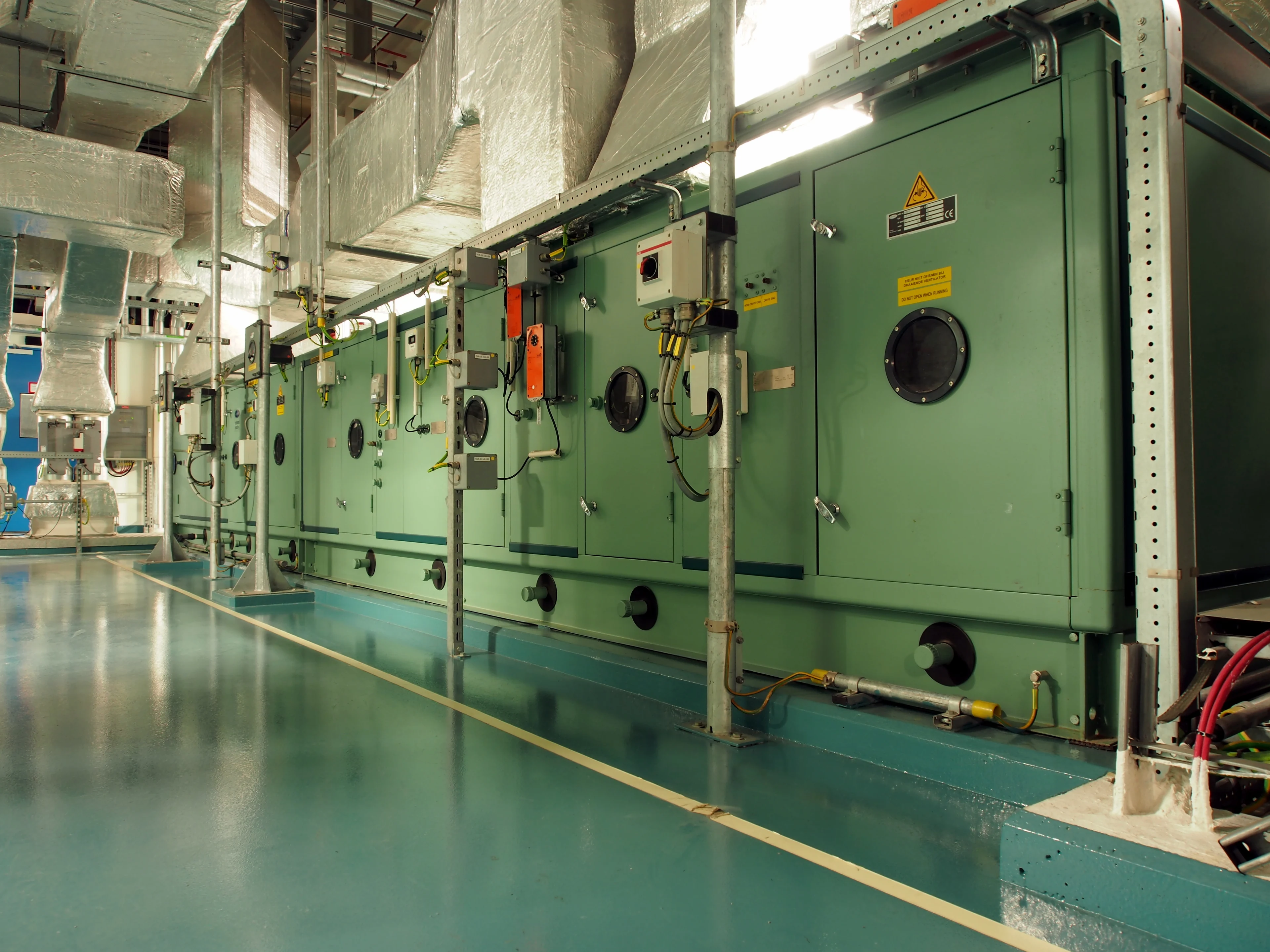 Unidade de tratamento de ar modular instalada, com automação, tubulações e dutos retangulares isolados em sala técnica; imagem de referência