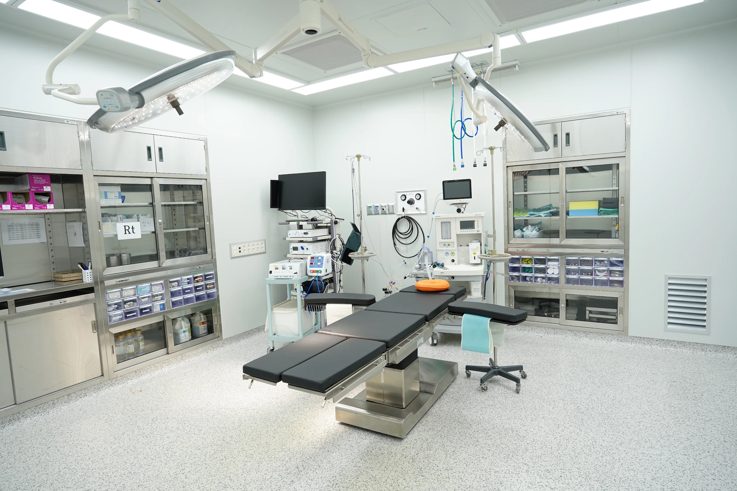 Sala cirúrgica vazia com mesa de operação, focos de luz e distribuição de ar no teto